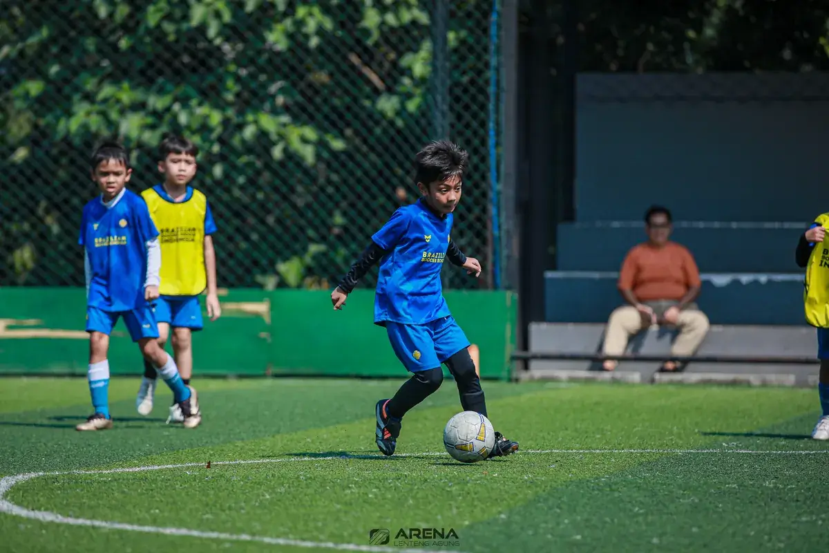 Anak menggiring bola di lapangan kecil