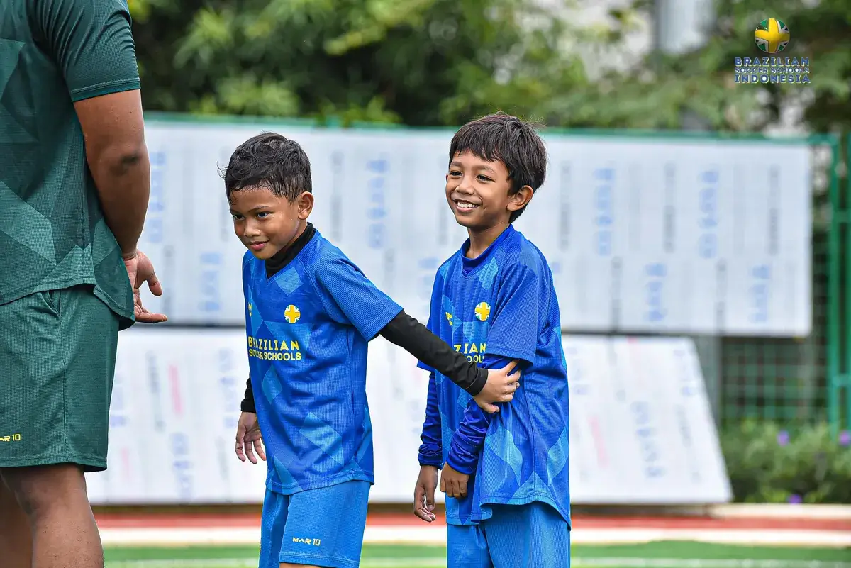 Anak-anak tertawa bersama teman saat sesi latihan sepak bola