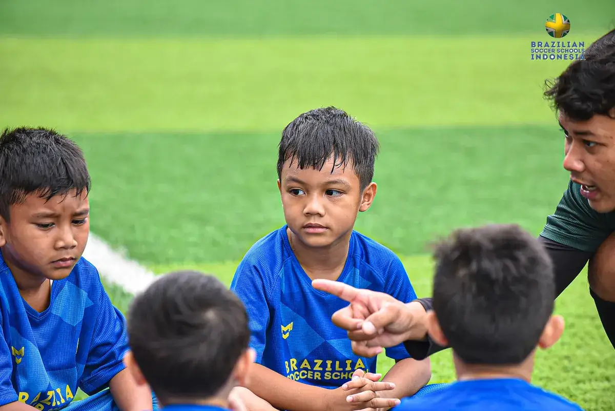 Anak tidak mau latihan sepak bola: pelatih mengajak anak-anak berdiskusi di lapangan