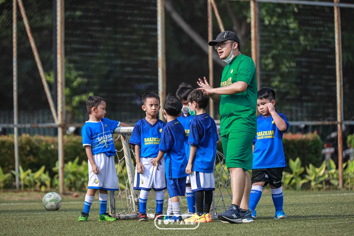 Pelatih BSS memberi instruksi kepada kelompok anak usia dini di lapangan